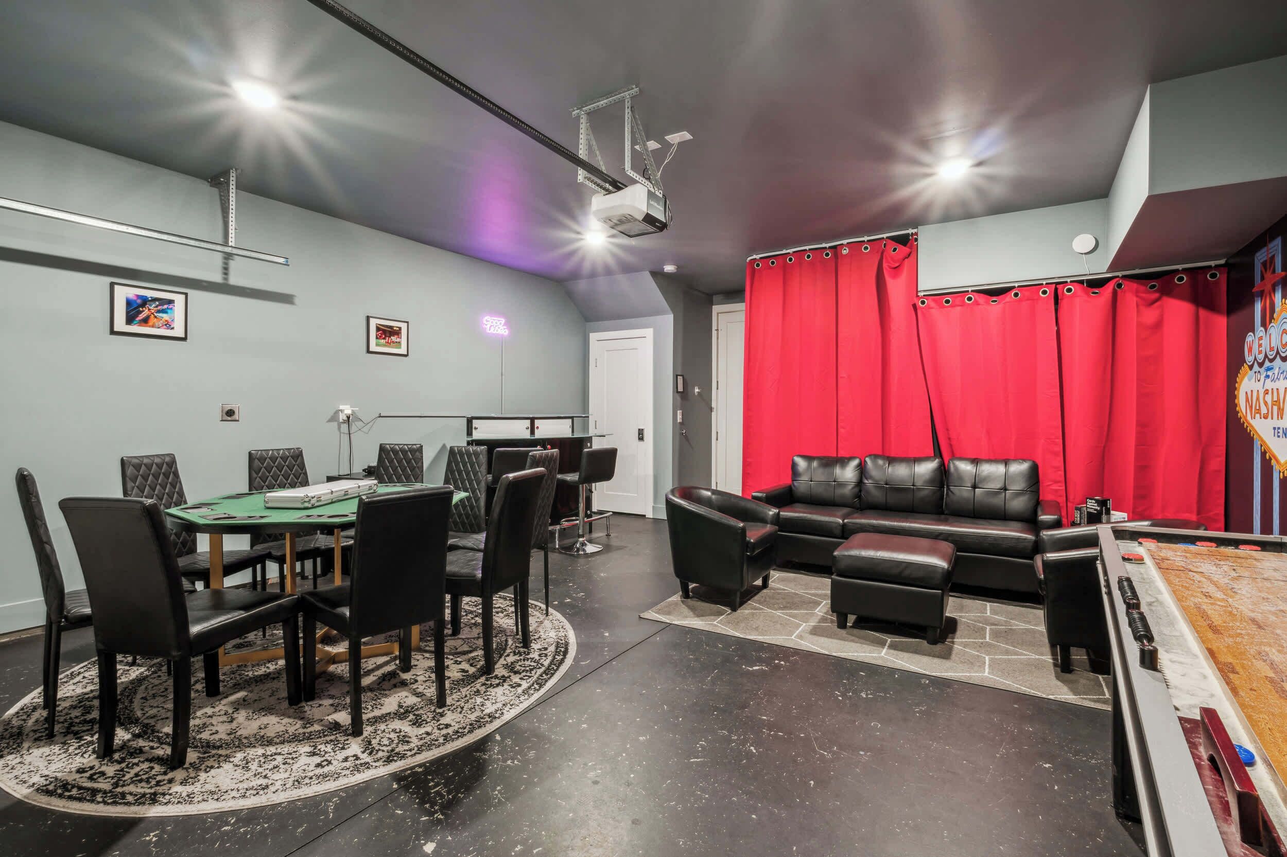 A room with a pool table, a leather sofa, a dining table with chairs, and a red curtain.