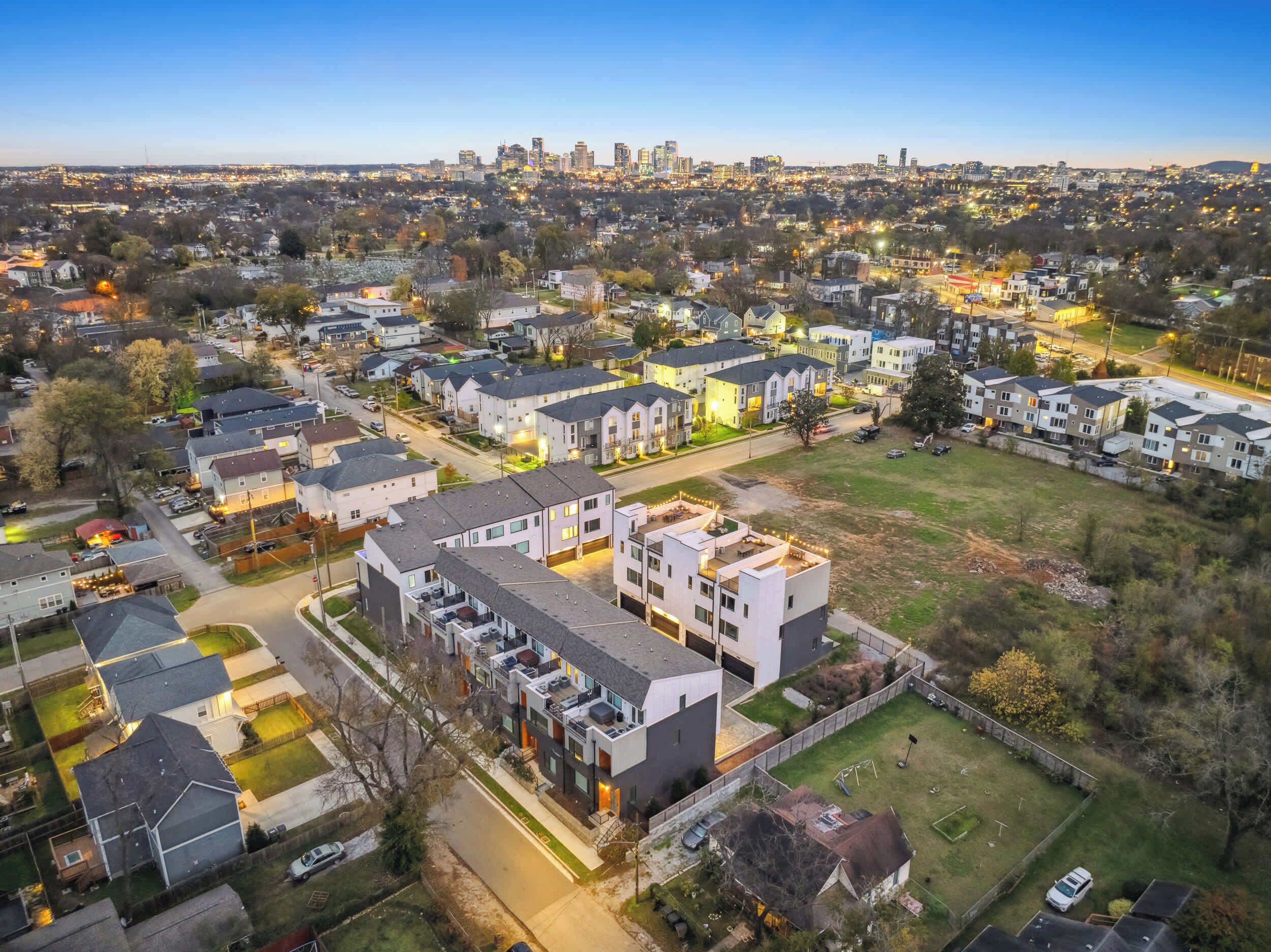 Ett bostadsområde med moderna hyreshus, en välskött gräsmatta och en avlägsen stadsbild i horisonten.