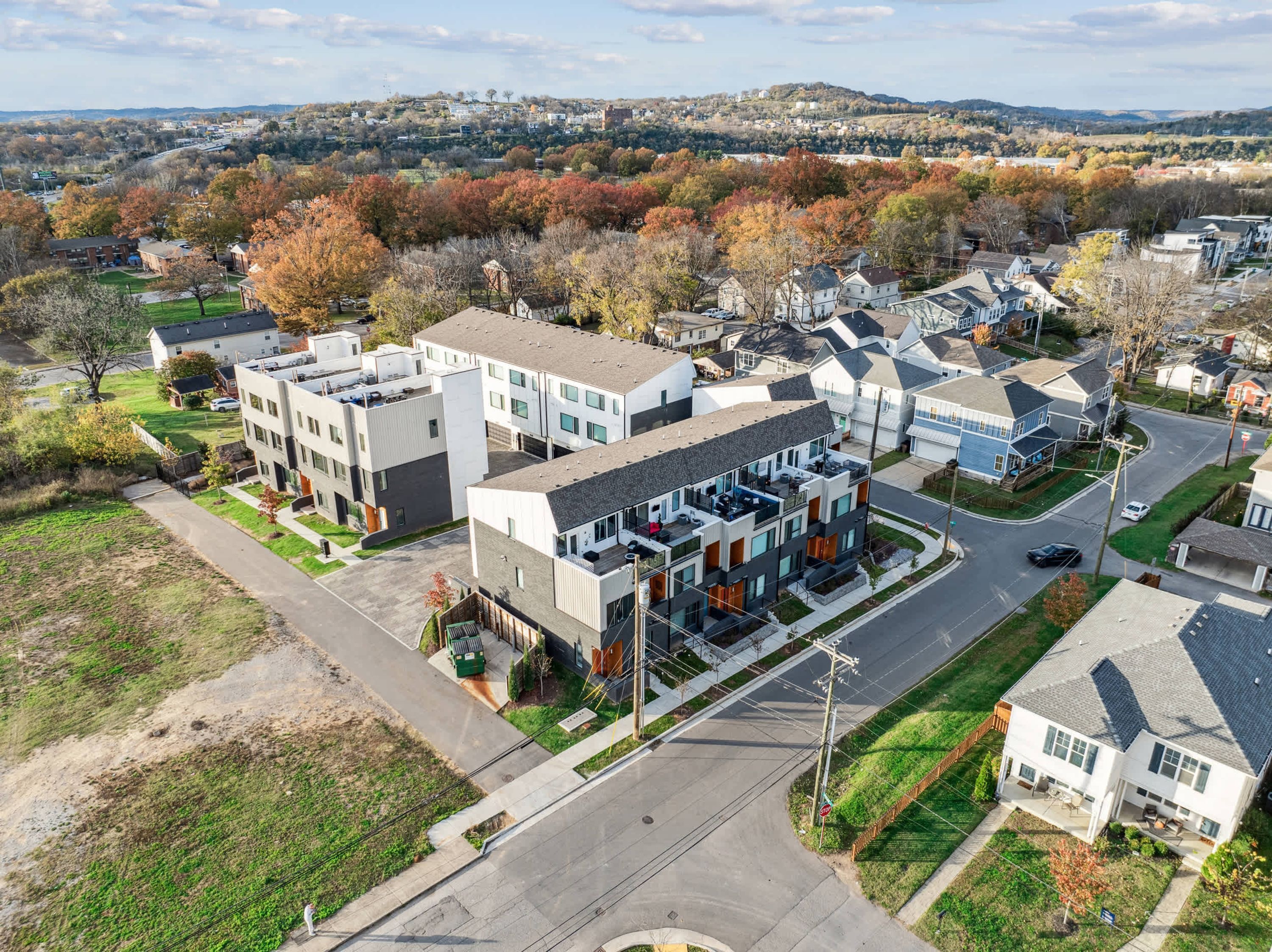Zona residencial con casas modernas, una avenida principal y un fondo montañoso.