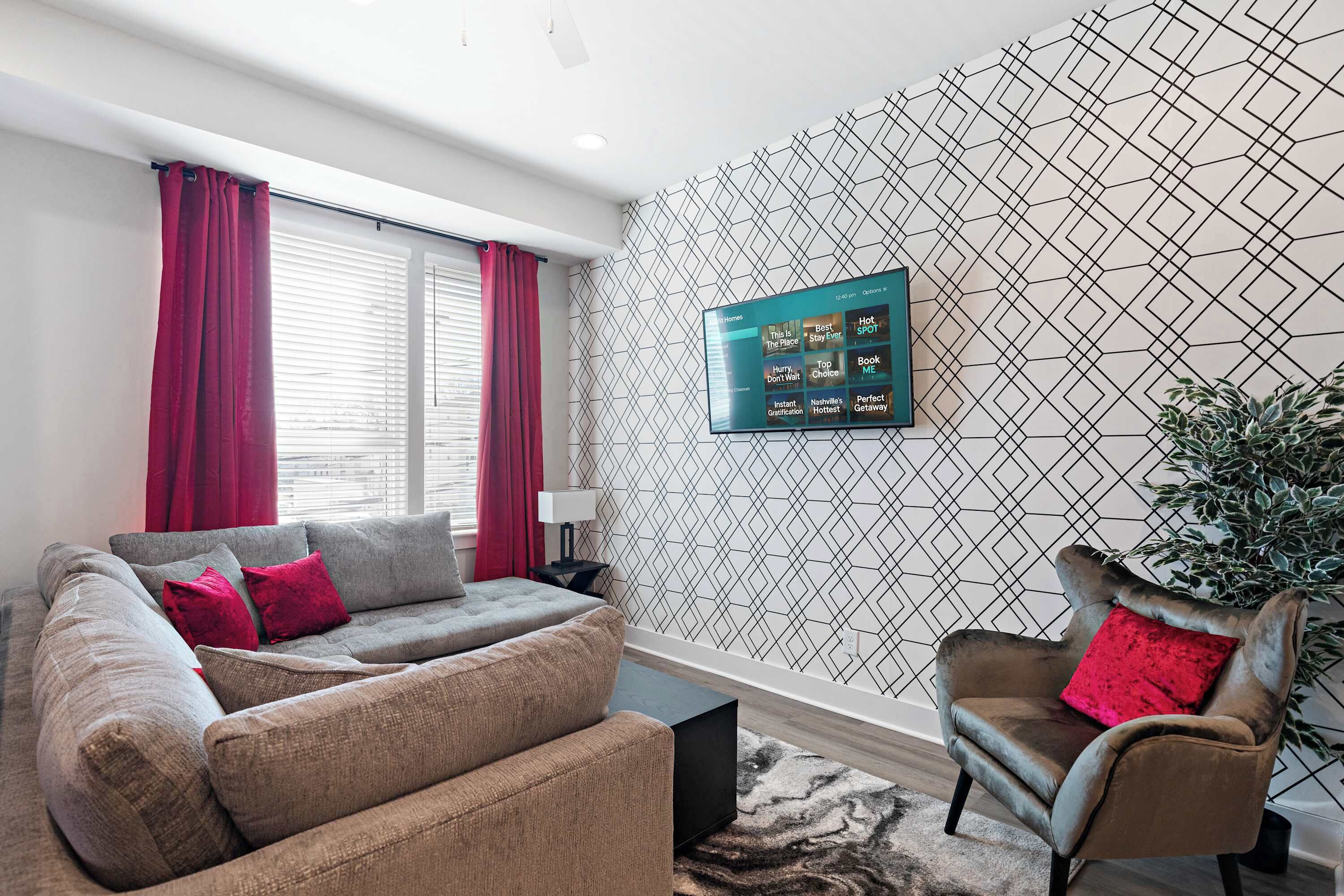 A modern living room with a grey sofa, a brown armchair, and a patterned wall.