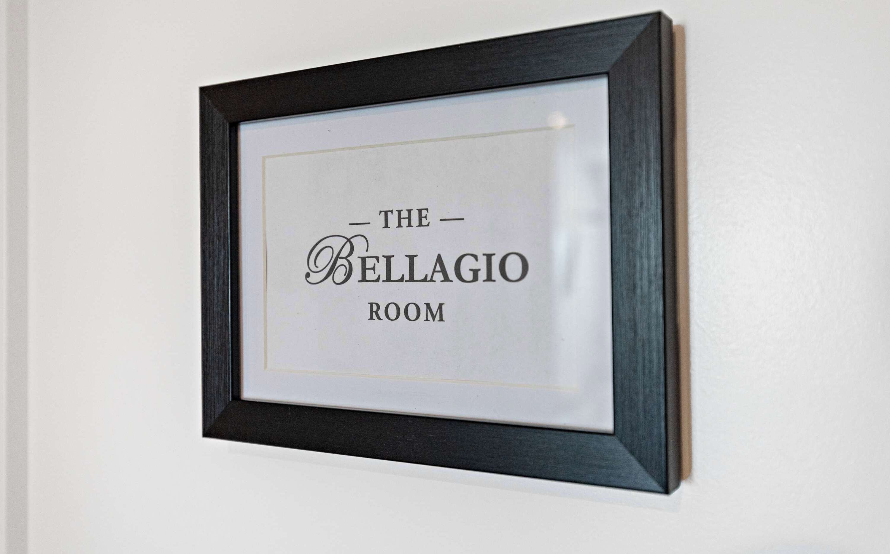 A framed sign with the text "The Bellagio Room" on a white wall.