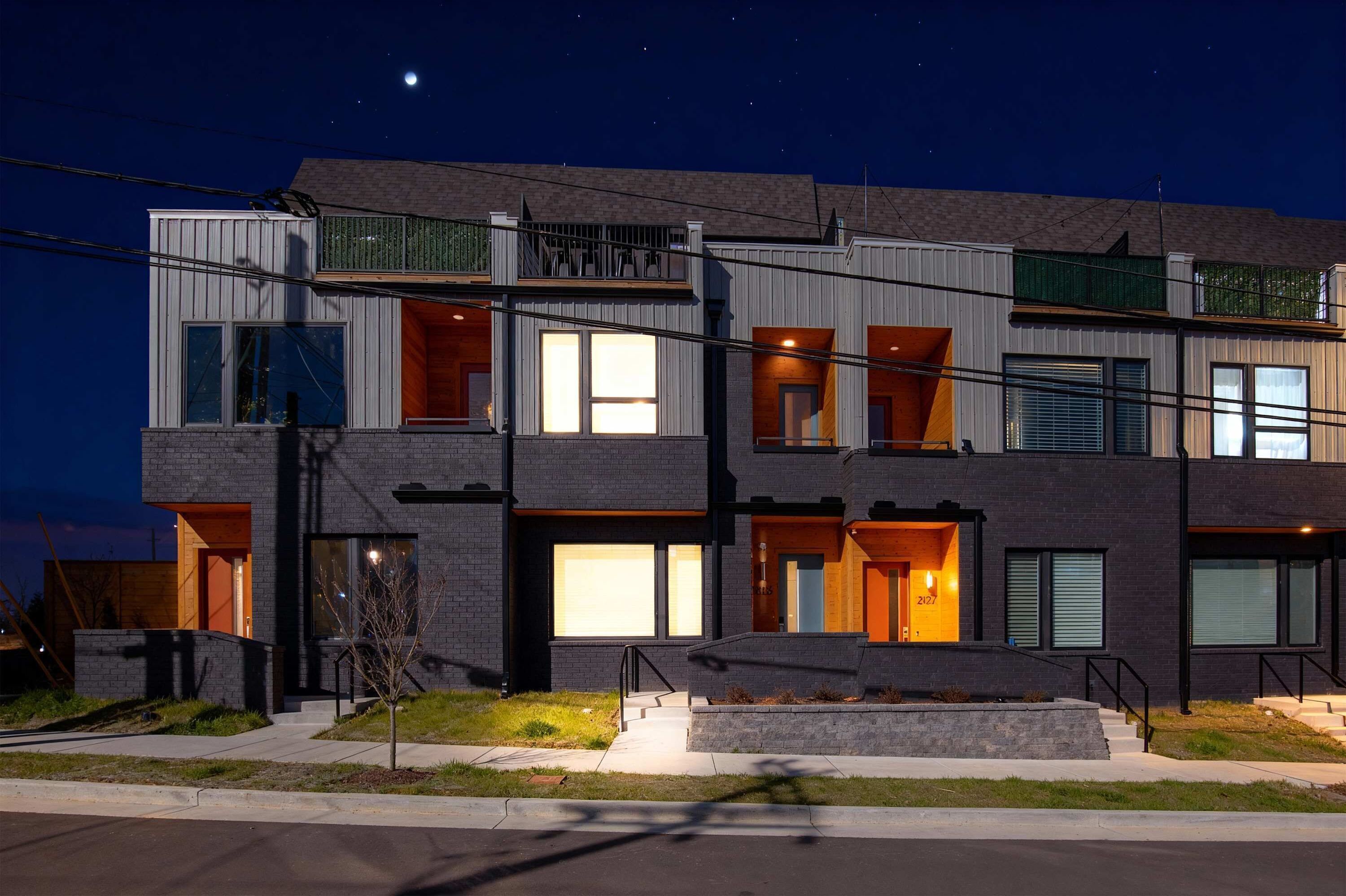 Een modern meerlaags gebouw met een balkon, grote ramen en een goed verlichte ingang.
