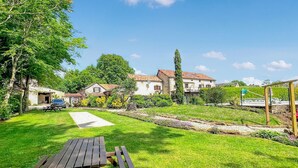 A grassy backyard with a picnic table, a stone pathway, and a row of houses with a garden and a pool. - 3 bedroom amazing home in Jouqueviel (Jouqueviel)