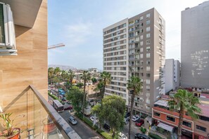 A high-rise building with multiple floors, a busy street with cars and a bus, and palm trees. - Luxury apartment with a pool, ocean view, air conditioning, and a digital fireplace (Lima)