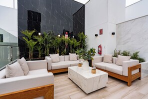 Un espace intérieur moderne avec un ensemble de canapés blancs, une table basse en marbre et des plantes en pot.