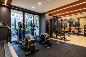 A gym with cardio machines, weightlifting equipment, and a mirror. - Luxury apartment with a pool, ocean view, air conditioning, and a digital fireplace (Lima)