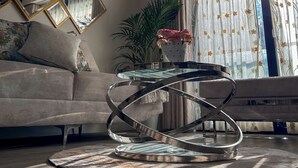 Ein modernes Wohnzimmer mit einem Glastisch, einer Couch und einem dekorativen Spiegel.