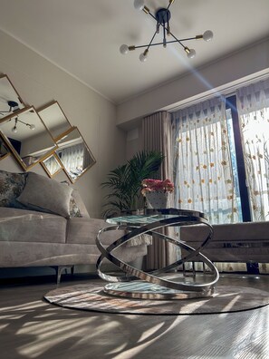 Uma sala de estar moderna com uma mesa de centro de vidro, um sofá e um espelho decorativo.