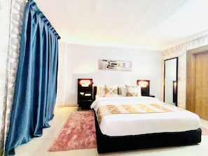 Ein Schlafzimmer mit einem Bett, Nachttischen, einer Wandleuchte und einer Tür.