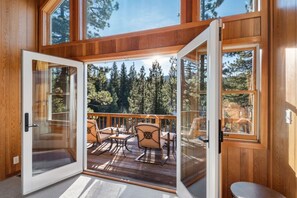 Une cabane en bois dotée d’une terrasse, de portes vitrées et offrant une vue sur les arbres.