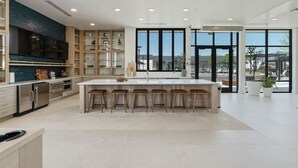 A modern kitchen with a large island, bar stools, and a view of the city through large windows. - Views! Amenities! Pool/Spa/Gym/Bowl/Pking! (Salt Lake City)