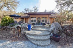 Una casa con una escalera de piedra que lleva a la puerta principal, rodeada de grandes rocas y un jardín.
