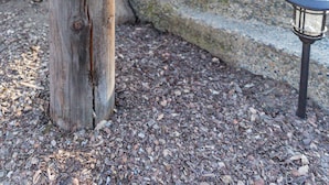 Une nichée à oiseaux en bois, conçue comme une petite maison, un pot de fleurs bleu et une lanterne posée sur une marche en pierre.