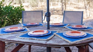 Une table ronde en bois, recouverte de sets de table bleus et de assiettes rouges, entourée de chaises.