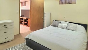 Een slaapkamer met een bed, een dressoir, een kledingkast en een televisie in de hoek.