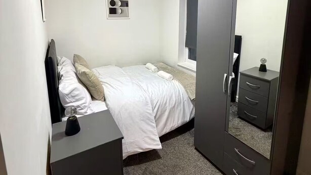 Ein Schlafzimmer mit einem Bett, einem Schminktisch, einem Spiegel und einer Deckenleuchte.