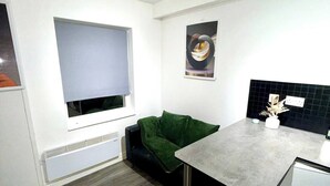 A compact kitchen with a dining table, a green sofa, a small refrigerator, and a window. - Lovely apartment in Preston perfect for your next getaway (Preston)