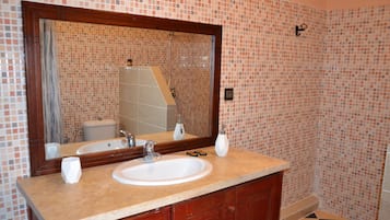 Un baño con un espejo grande, dos lavamanos y una ducha.