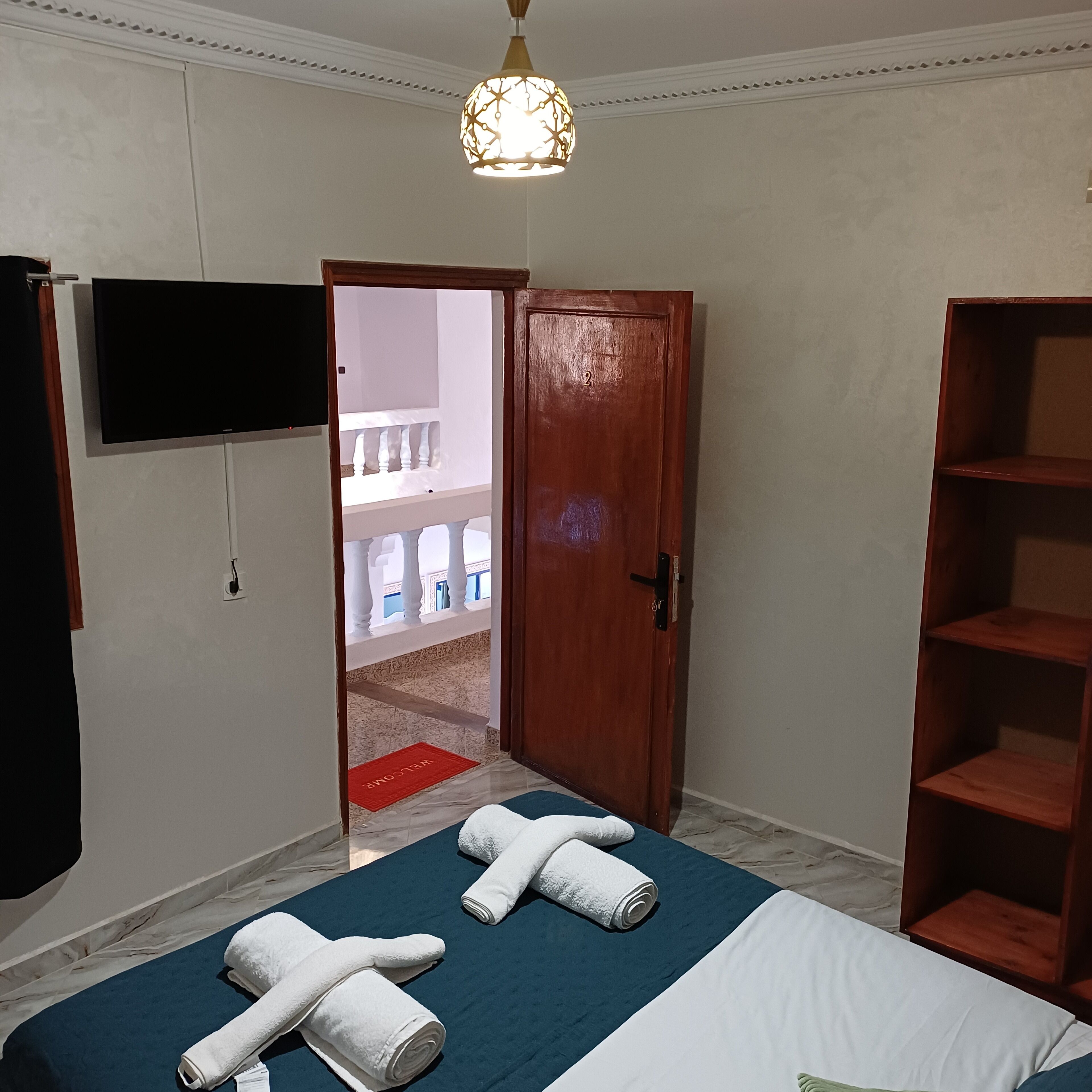 Una camera da letto con un letto, una TV, una porta in legno e un corridoio.
