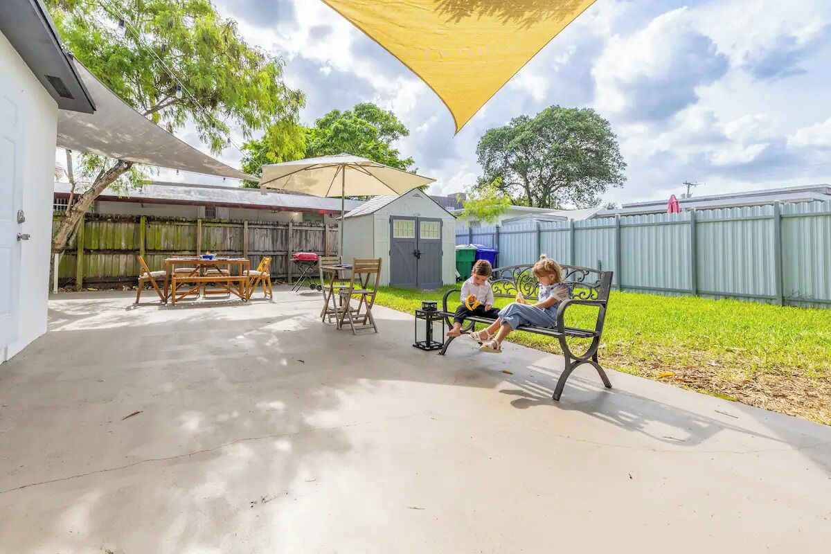 An outdoor patio area with a table and chairs, a bench, and a covered seating area.