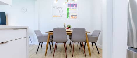 A modern kitchen with a dining area featuring a wooden table and grey chairs.