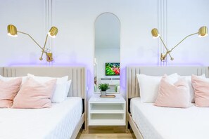 Quarto de hotel com duas camas, um espelho grande e luminárias fixadas na parede.