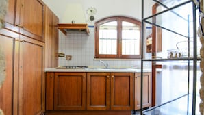 A kitchen with wooden cabinets, a stove, and a window. - 3 bedroom awesome home in Costa Rei (Costa Rei)