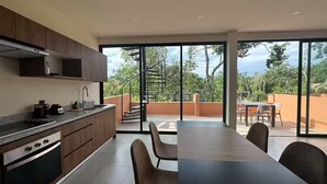 Et moderne køkken med spiseplads, store vinduer og en trappe til en balkon.