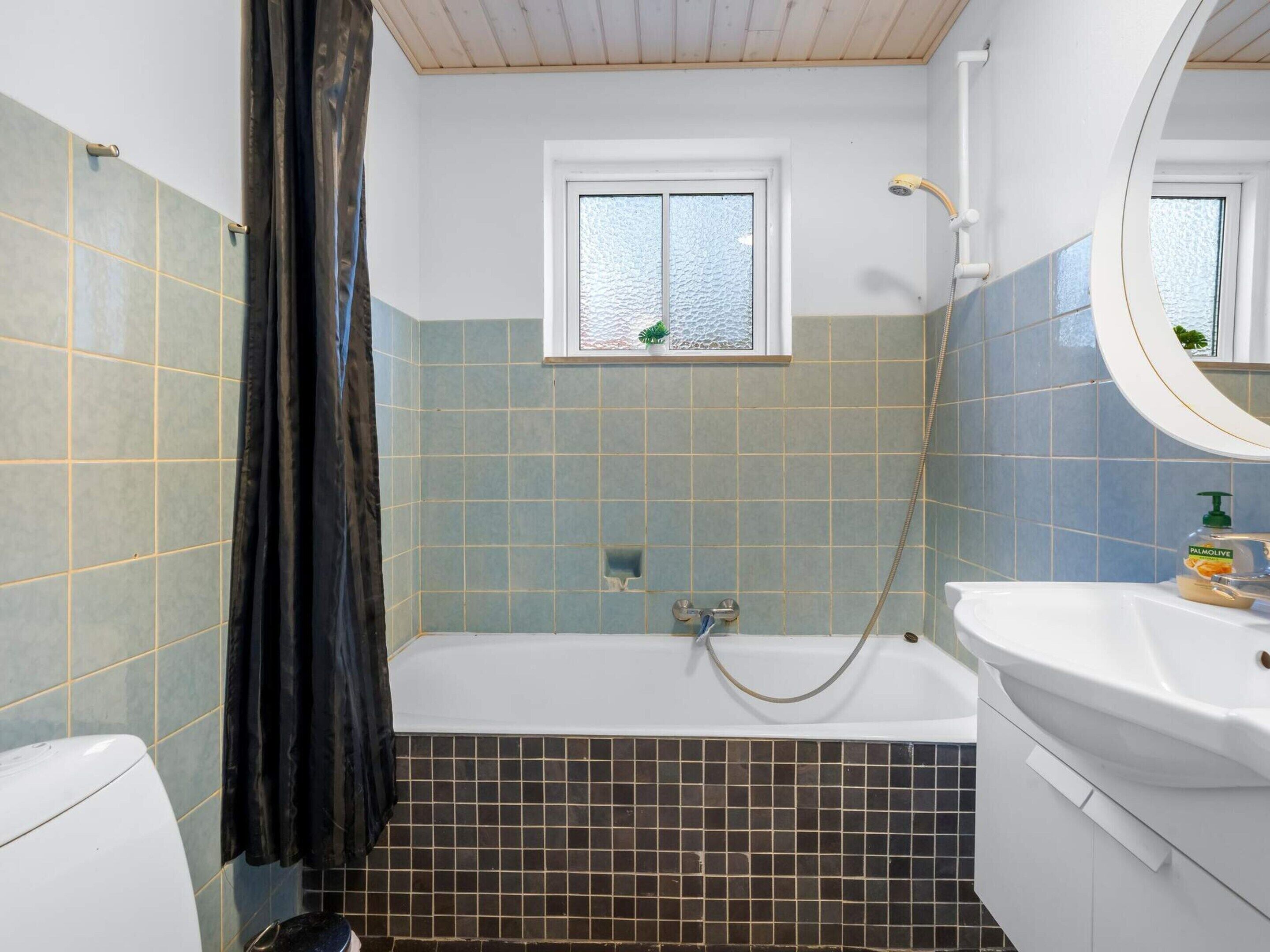 A bathroom with a bathtub, a window, a shower, and a sink.