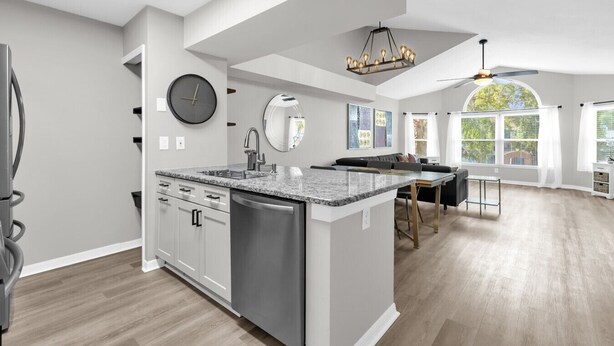A modern kitchen with a central island, built-in appliances, and a large window providing natural light. - Resort Stay~Near Disney~Bright~Gym~Hot Tub (Kissimmee)