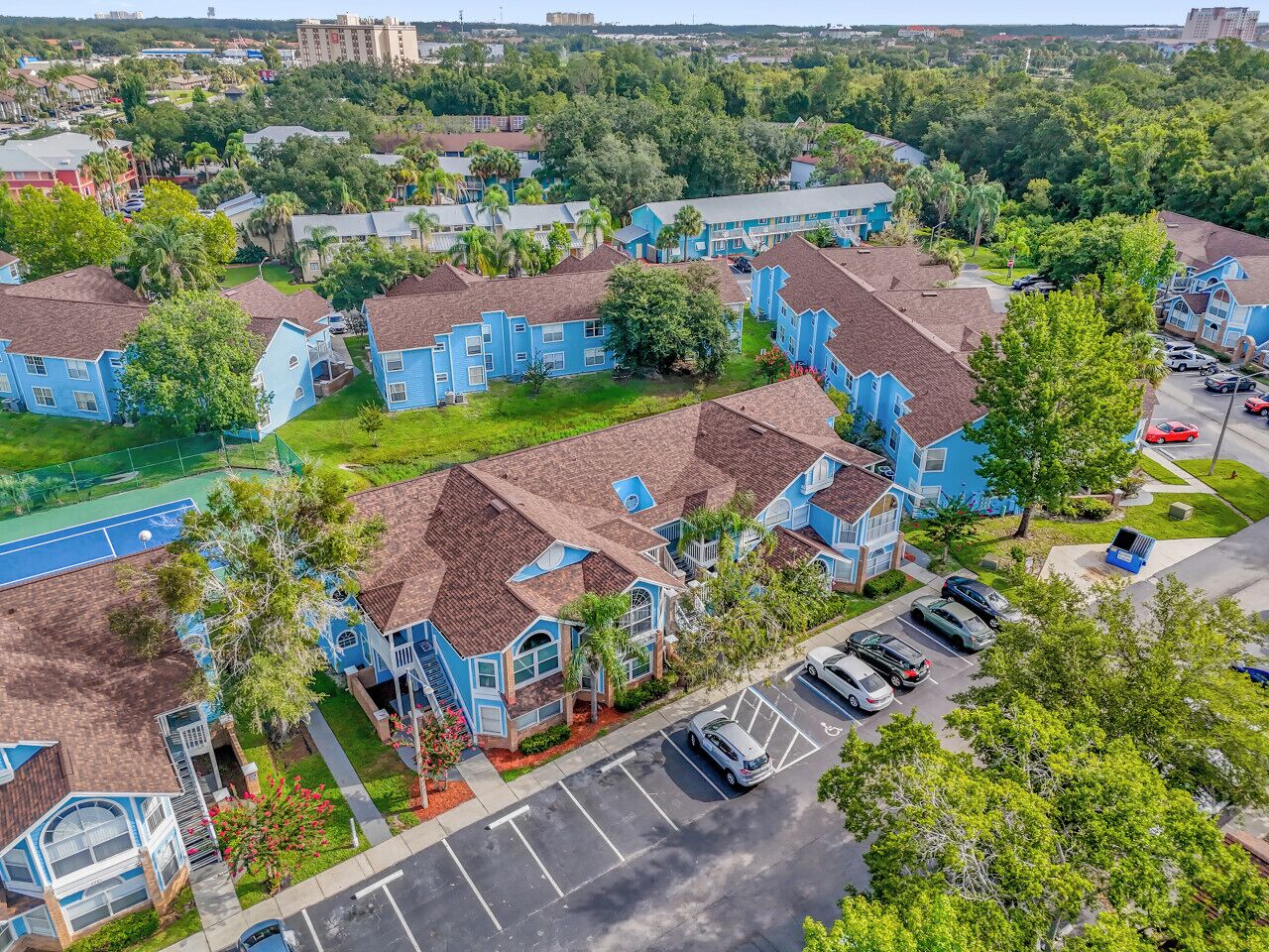 A residential area with blue houses, a tennis court, and a parking lot.