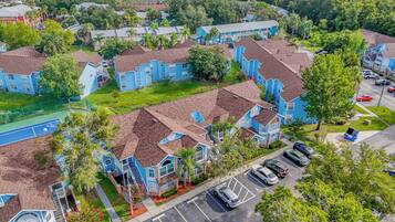 A residential area with blue houses, a tennis court, and a parking lot.
