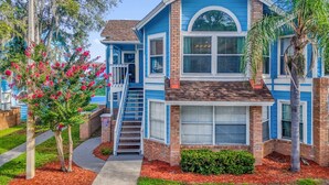 A two-story house with a blue exterior, a front porch, and a staircase leading to the second floor. - Resort Stay~Near Disney~Bright~Gym~Hot Tub (Kissimmee)