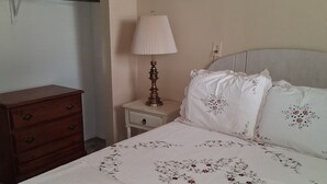 Une chambre à coucher avec un lit, une table de chevet, une lampe et une commode en bois.