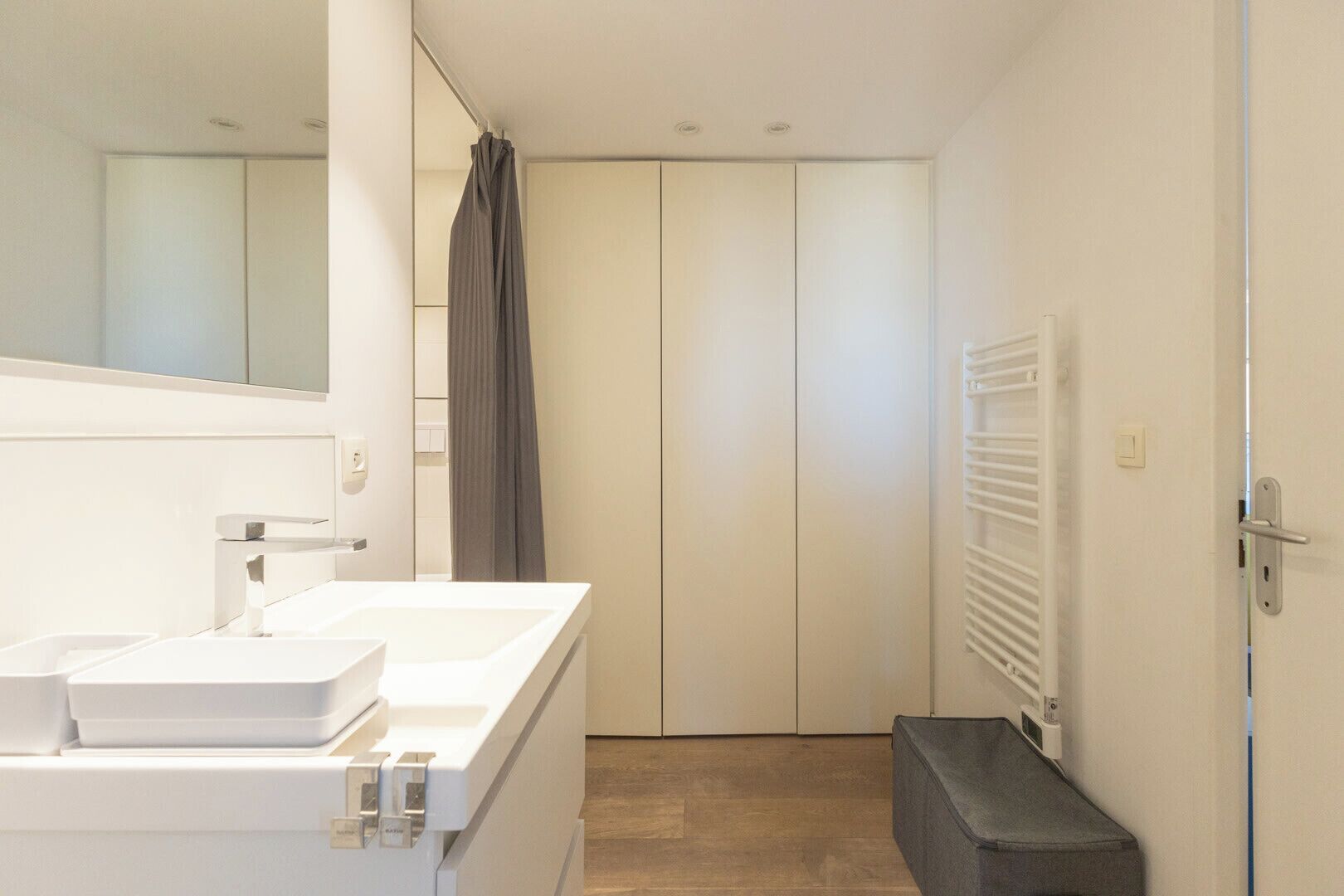 A modern bathroom with a white vanity, a shower curtain, and a towel rack.
