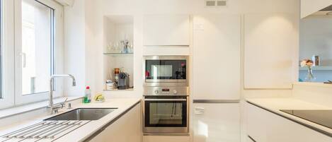 A compact kitchen with a built-in oven, microwave, and a small window.