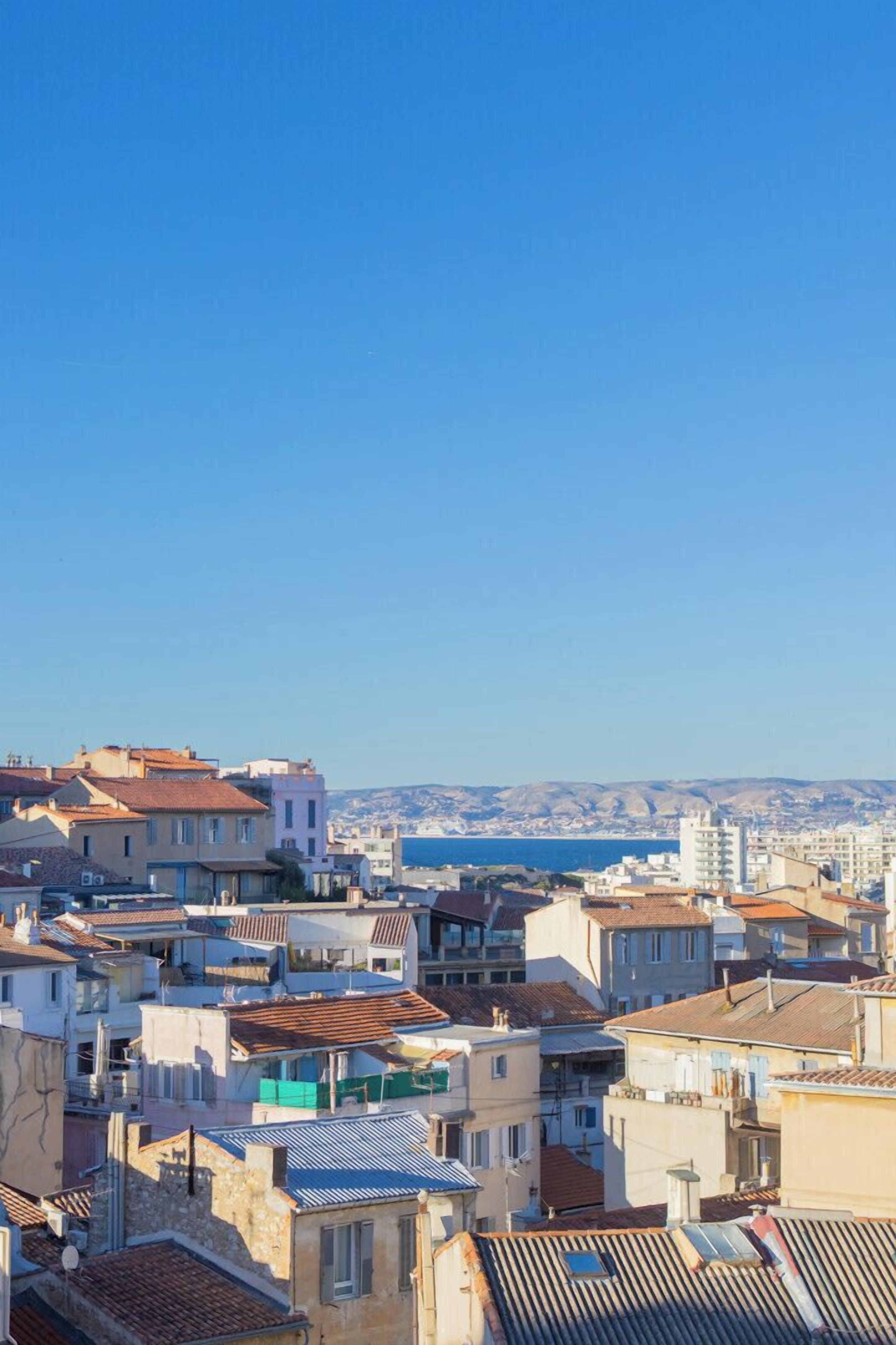 Un paisaje urbano costero con edificios densamente agrupados, algunos con balcones y terrazas visibles.