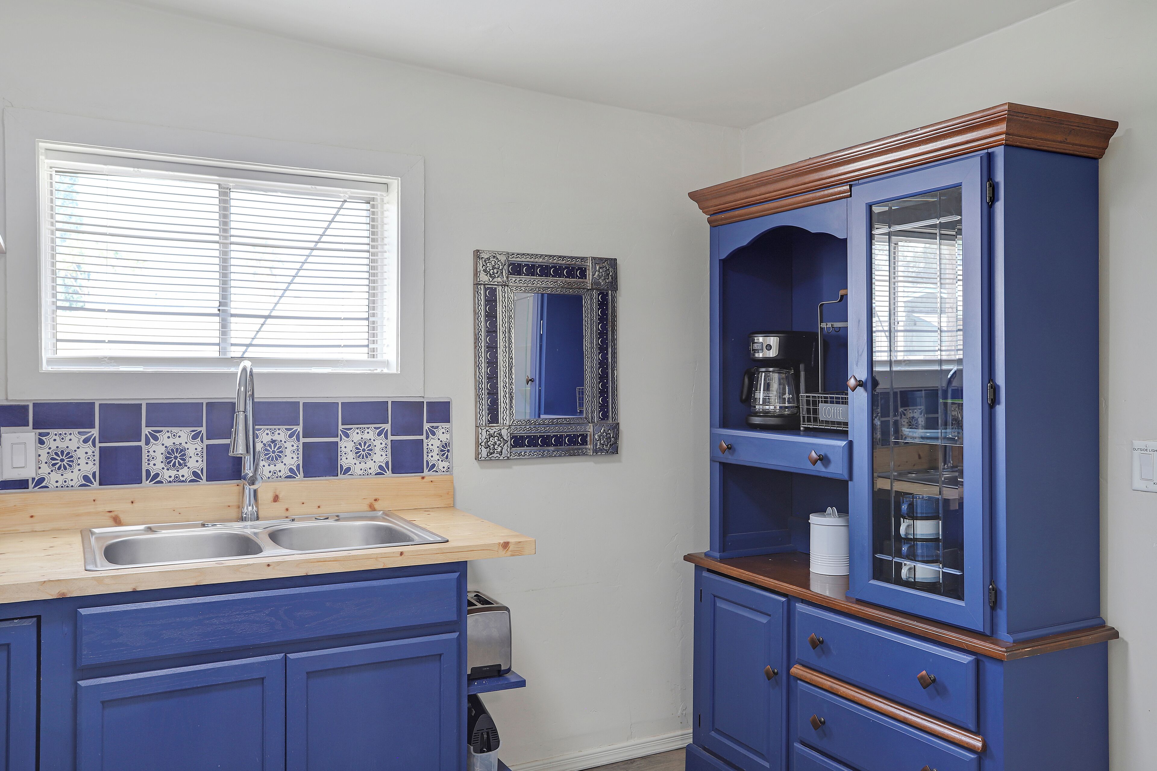 A kitchen with a double sink, a toaster, and a cabinet with glass doors.