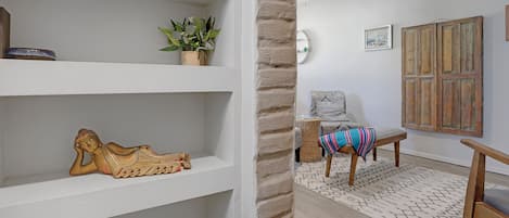 A room with white shelves, a wooden bench, a patterned rug, and a ceiling fan.