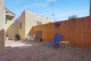 A backyard with a wooden fence, a blue chair, and a small table. - Cozy 1-bedroom apartment in peaceful Las Cruces with AC (Las Cruces)