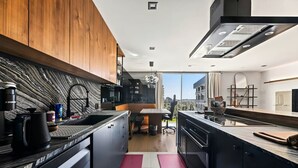 A modern kitchen with a central island, wooden cabinets, and a view of the city. - Modern Cozy 1-bedroom condo in Beverly Hills (Los Angeles)