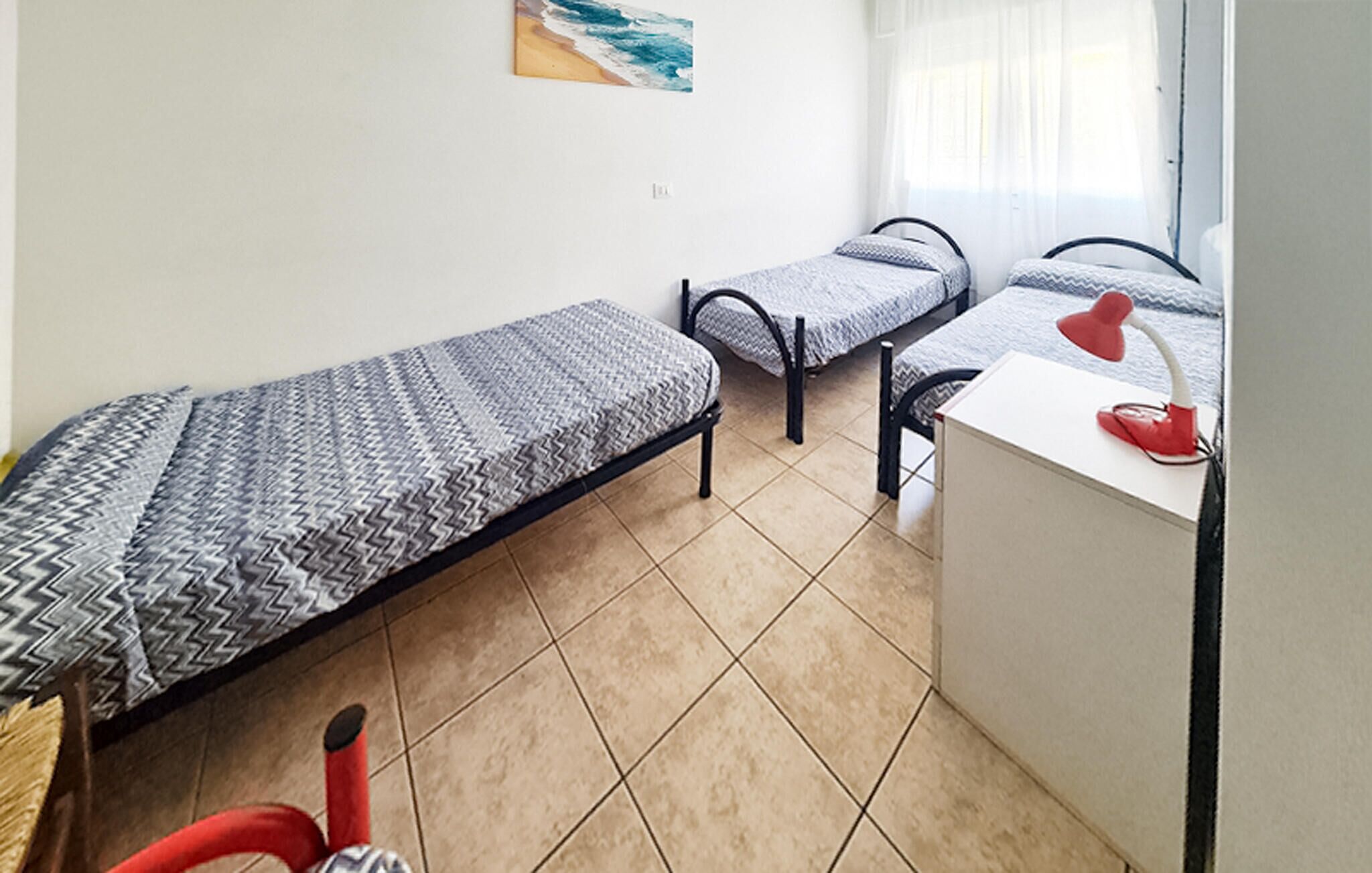 A small, tidy room with two single beds, a desk, and a chair.