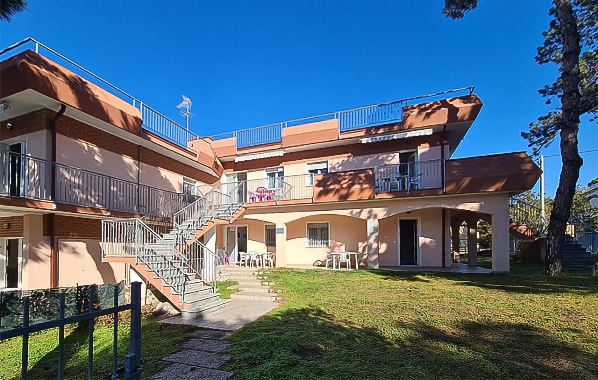 Un edificio a più piani con balconi, una scala e area salotto all'aperto.