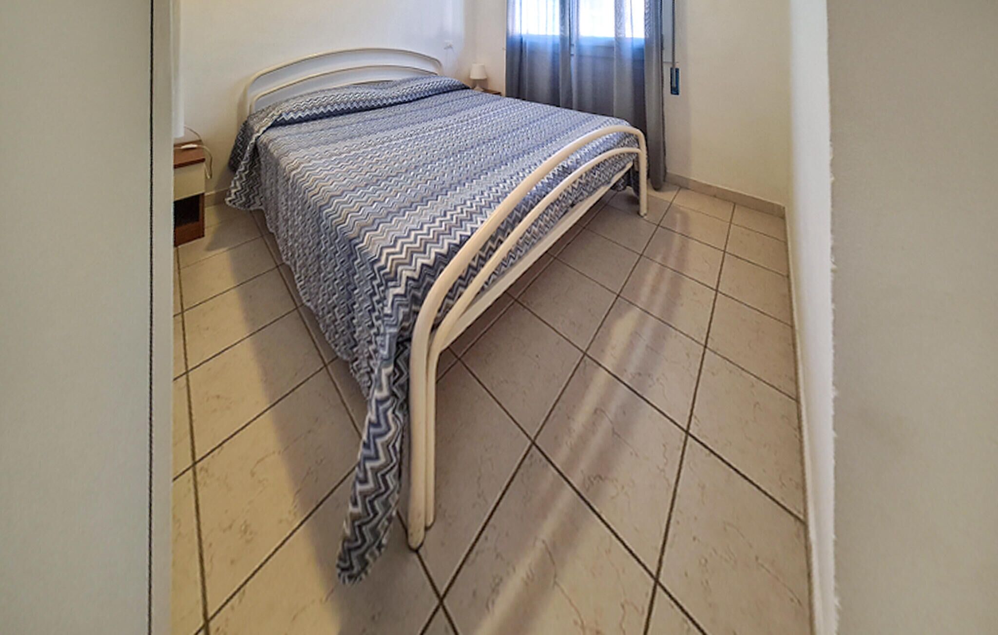 Une chambre à coucher avec un lit, une table de chevet et une fenêtre avec des rideaux.