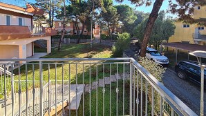 Un quartier résidentiel avec des balcons, une cour verdoyante et des voitures garées.