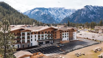 A multi-story hotel with a ski resort view, featuring a parking lot and mountainous backdrop.