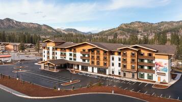 A multi-story hotel with a parking lot, surrounded by mountains.