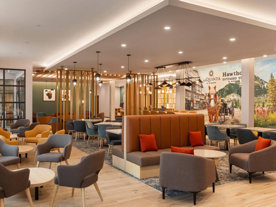 A modern lounge area with seating arrangements, a large mural, and a ceiling with recessed lighting.