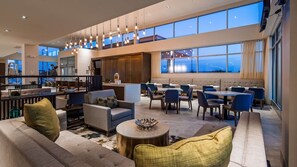 A spacious hotel lobby with a high ceiling, modern furniture, and large windows offering a view of the cityscape. - Hawthorn Extended Stay Austin North (Austin)