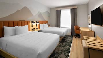 Habitación de hotel con dos camas, un escritorio, una silla, un televisor y una ventana con cortinas.